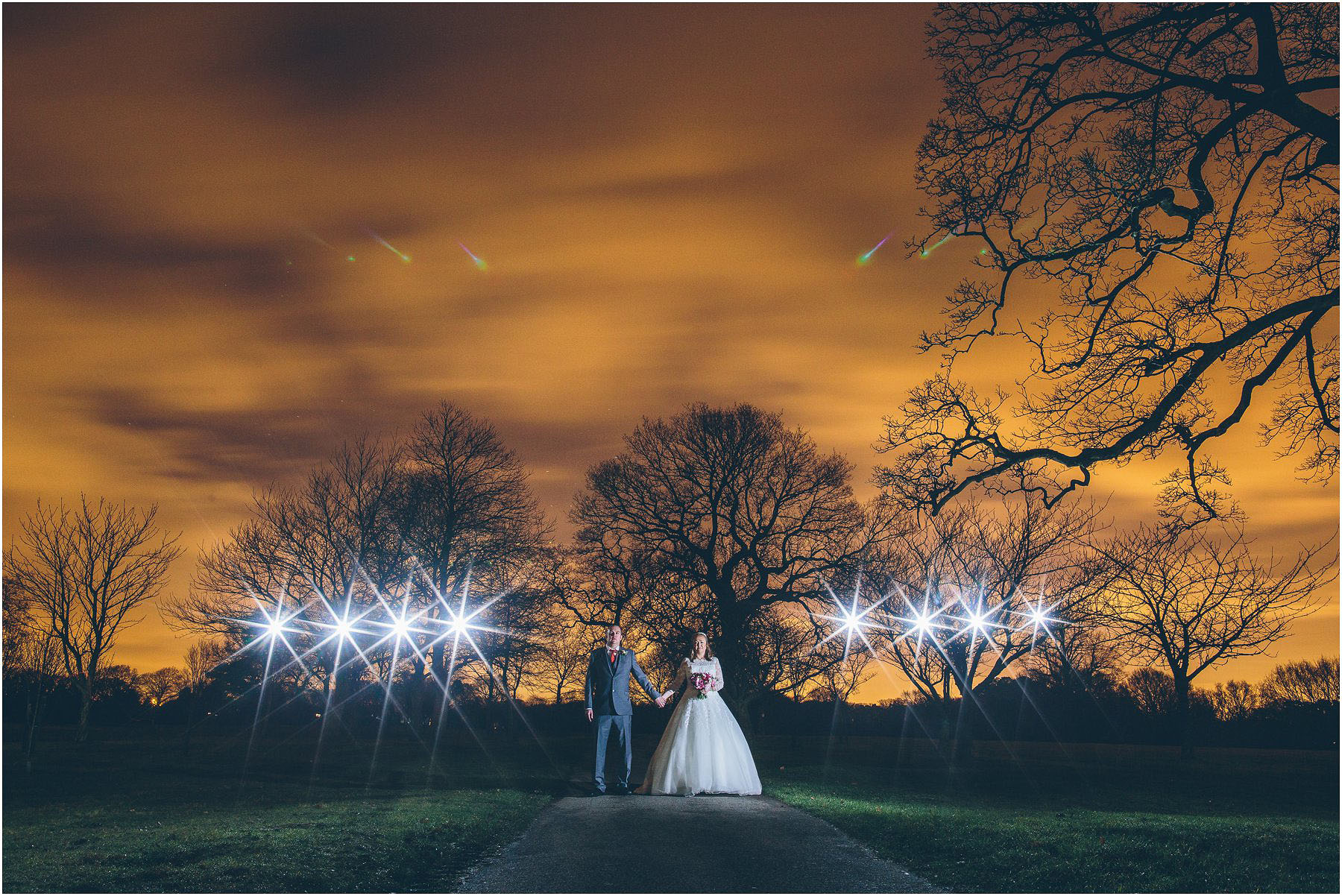 A night time wedding portrait with floodlights in the background taken at Mere Court in Manchester