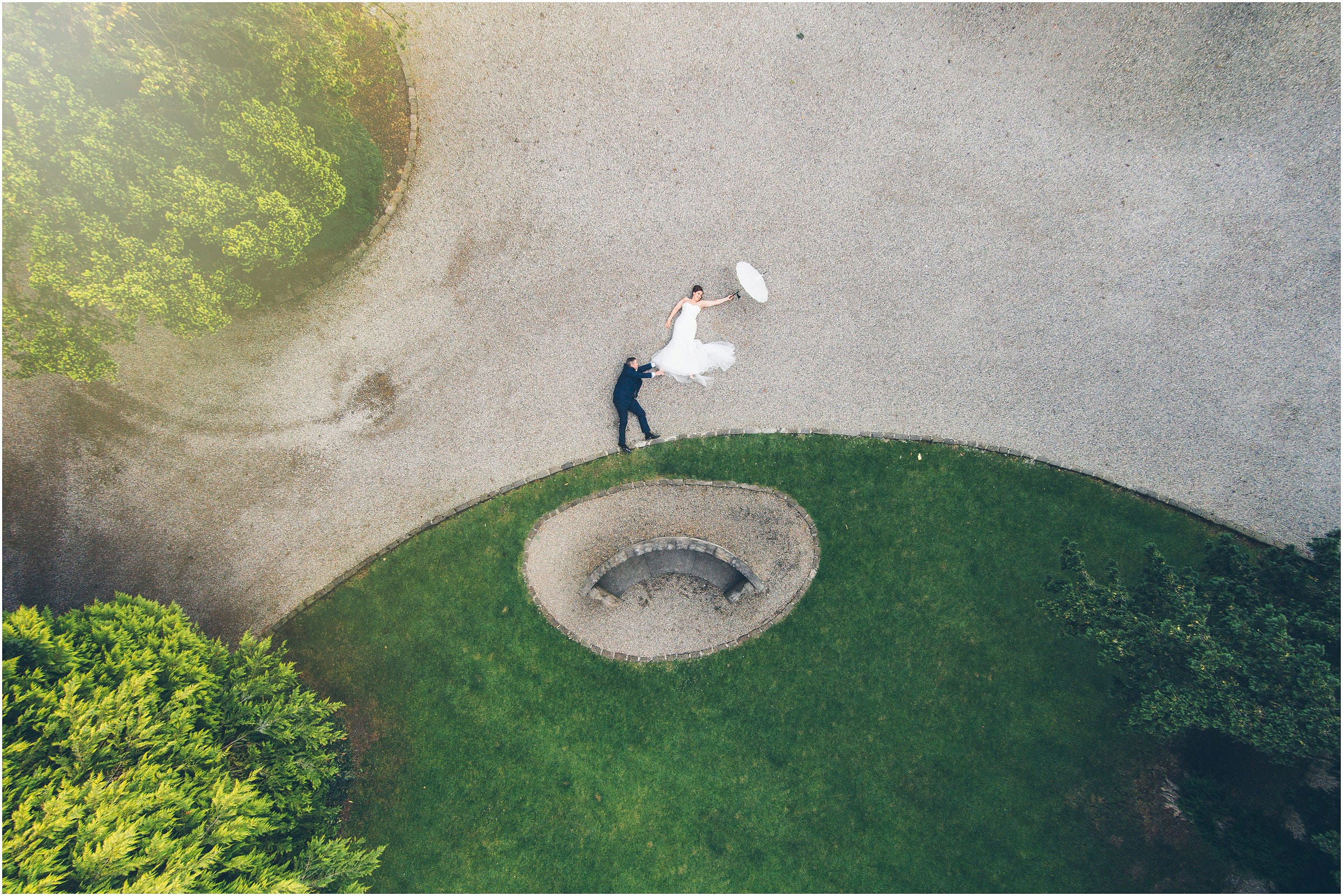 An amazing wedding photo taken by a drone at Mitton Hall in Manchester showing a couple with an umbrella looking like they're flying