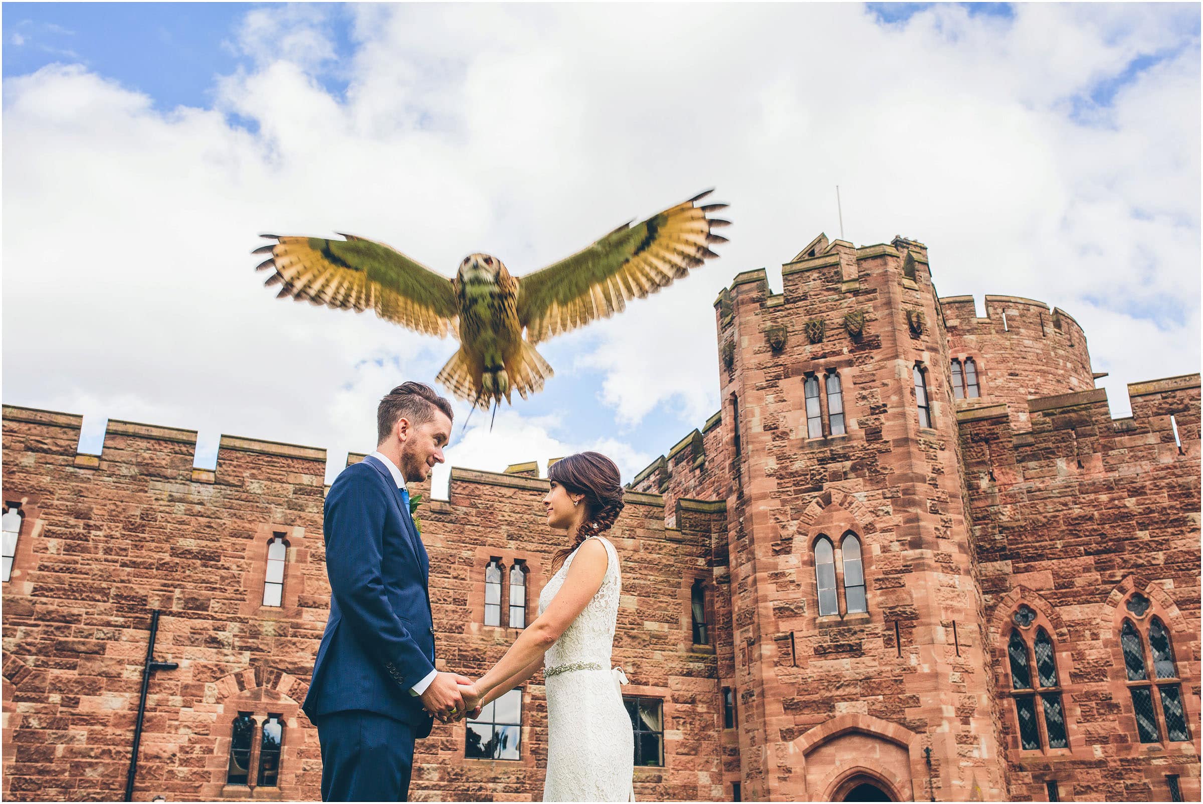 A bird of prey flies over the heads of a bride and groom at their Peckforton Castle wedding