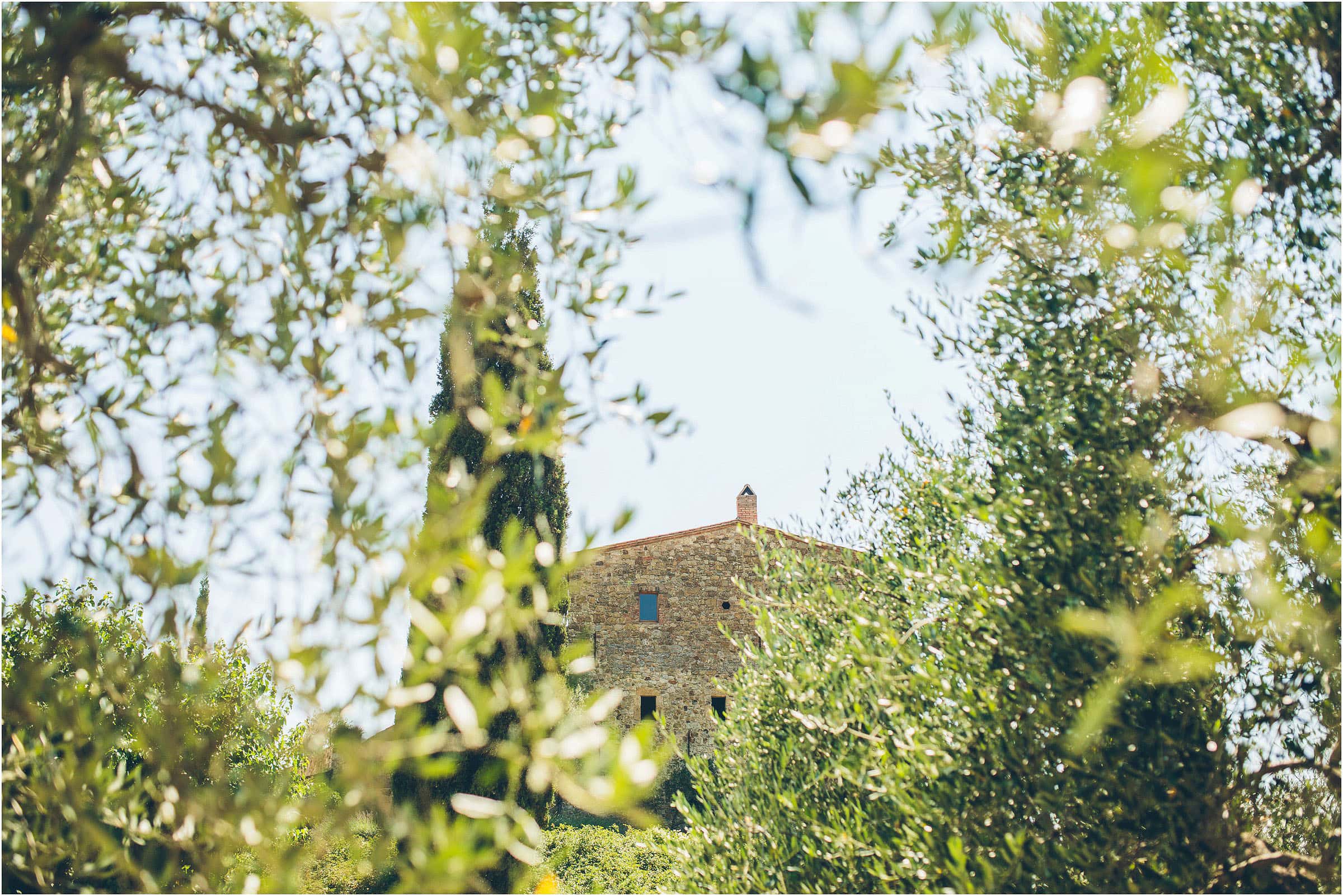 Exterior photo of Castello di Vicarello in Tuscany taken through some trees on the morning of a wedding