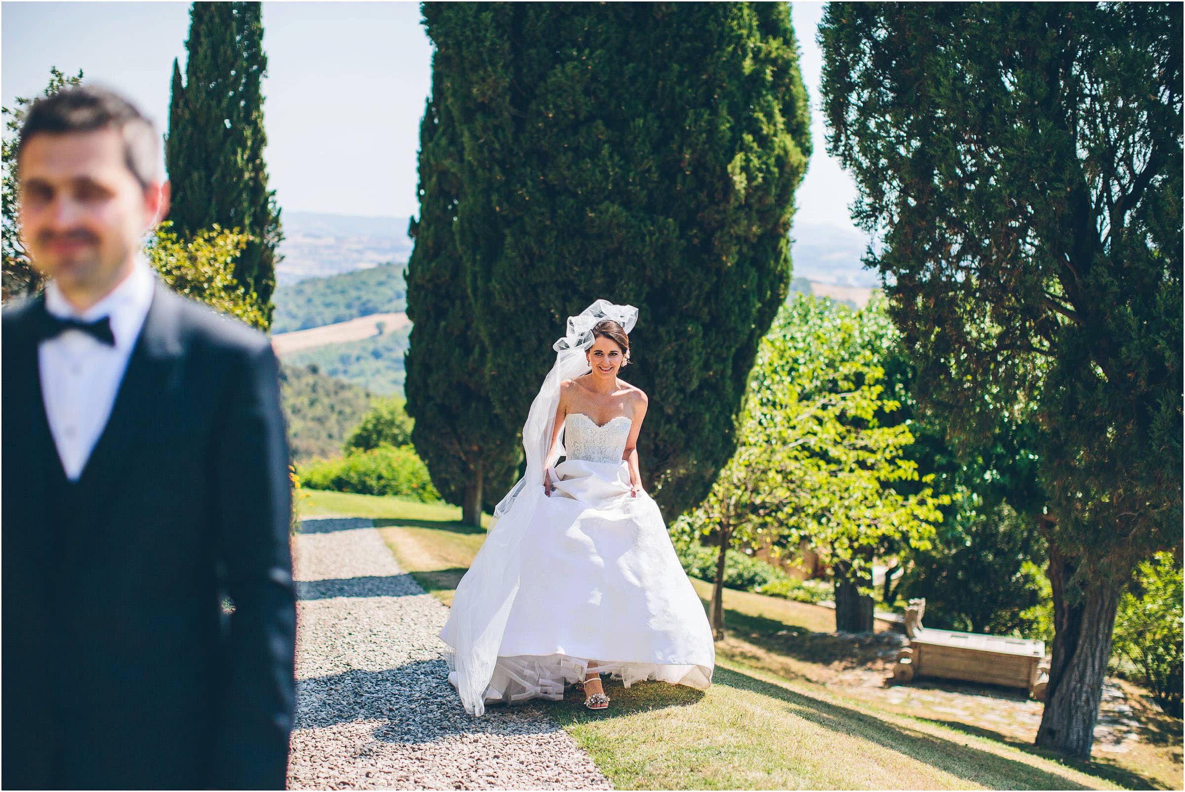 A wedding photo showing the bride approaching Castello di Vicarello in Tuscany in bright sunshine