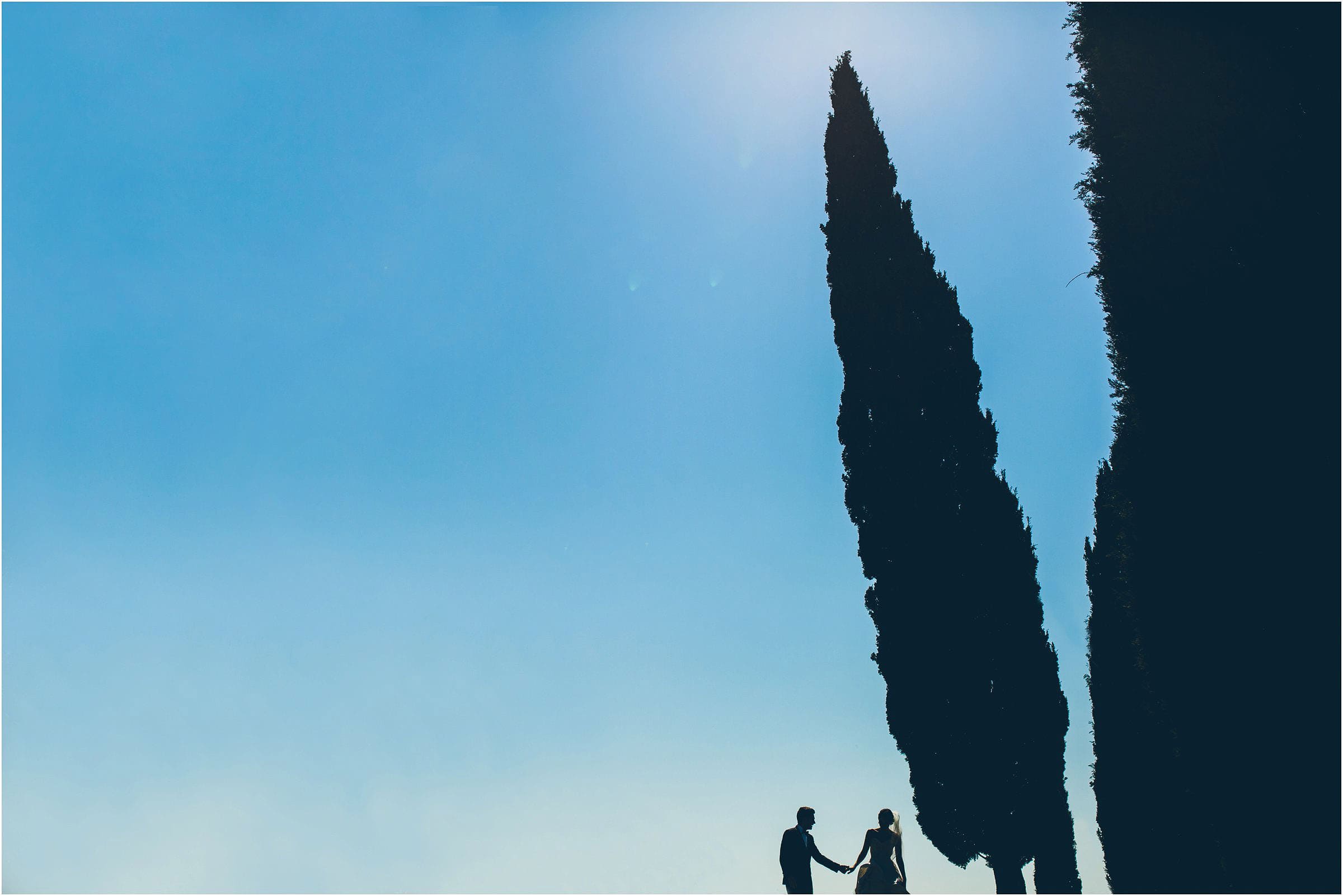 Stunning photo of a bride and groom silhouetted against a dusty blue sky on their wedding at Castello di Vicarello in Tuscany