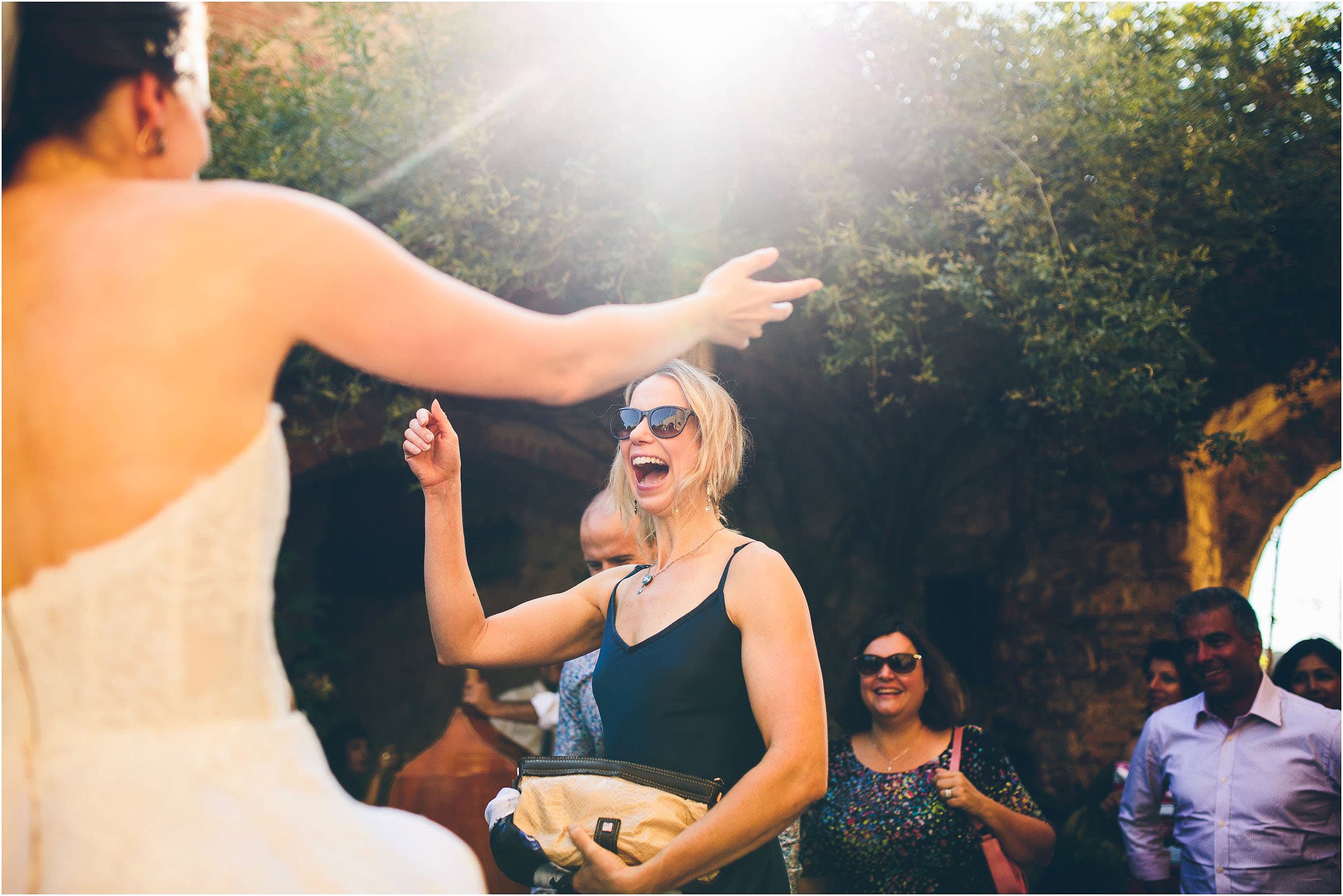 A wedding guest in a black dress and sunglasses arrives at Castello di Vicarello in Tuscany to greet the bride