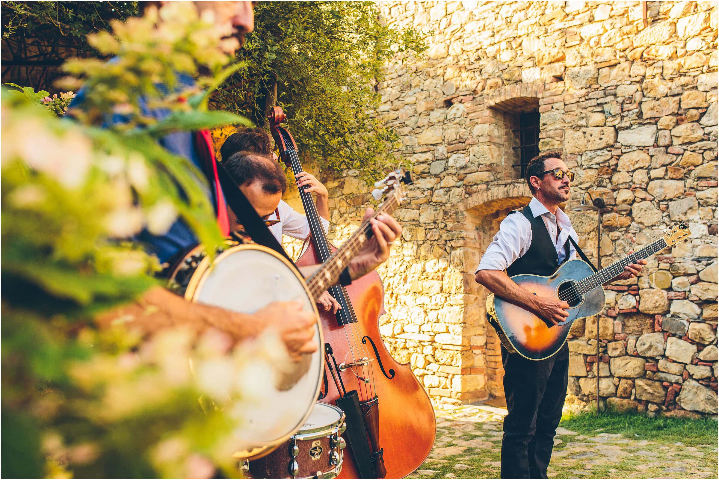 At Castello di Vicarello in Tuscany a wedding band plays in the sunshine with a guitar, double bass, banjo and a snare drum