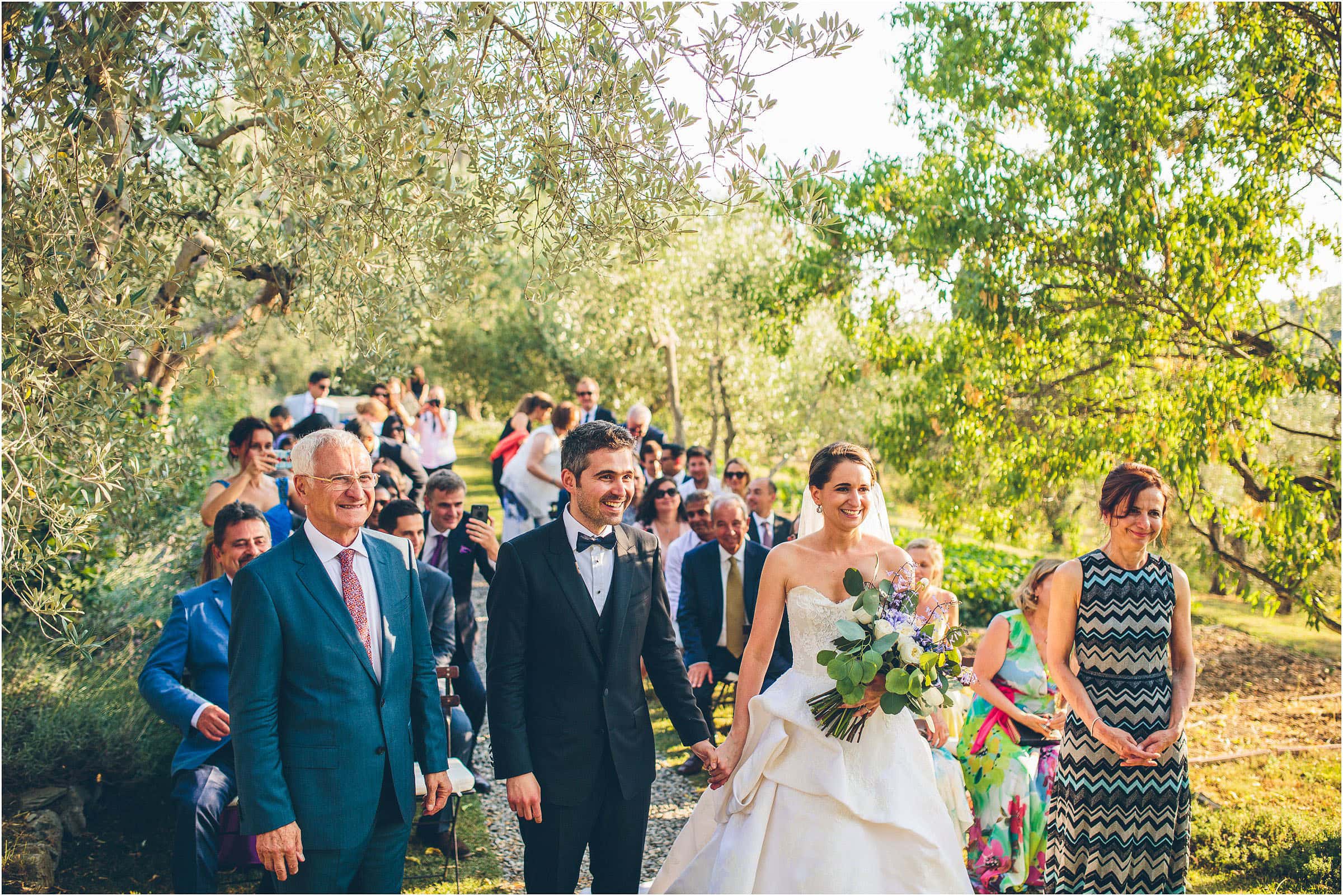 The bride and groom hold hands in front of guests in a photo by destination wedding photographer The Crawleys