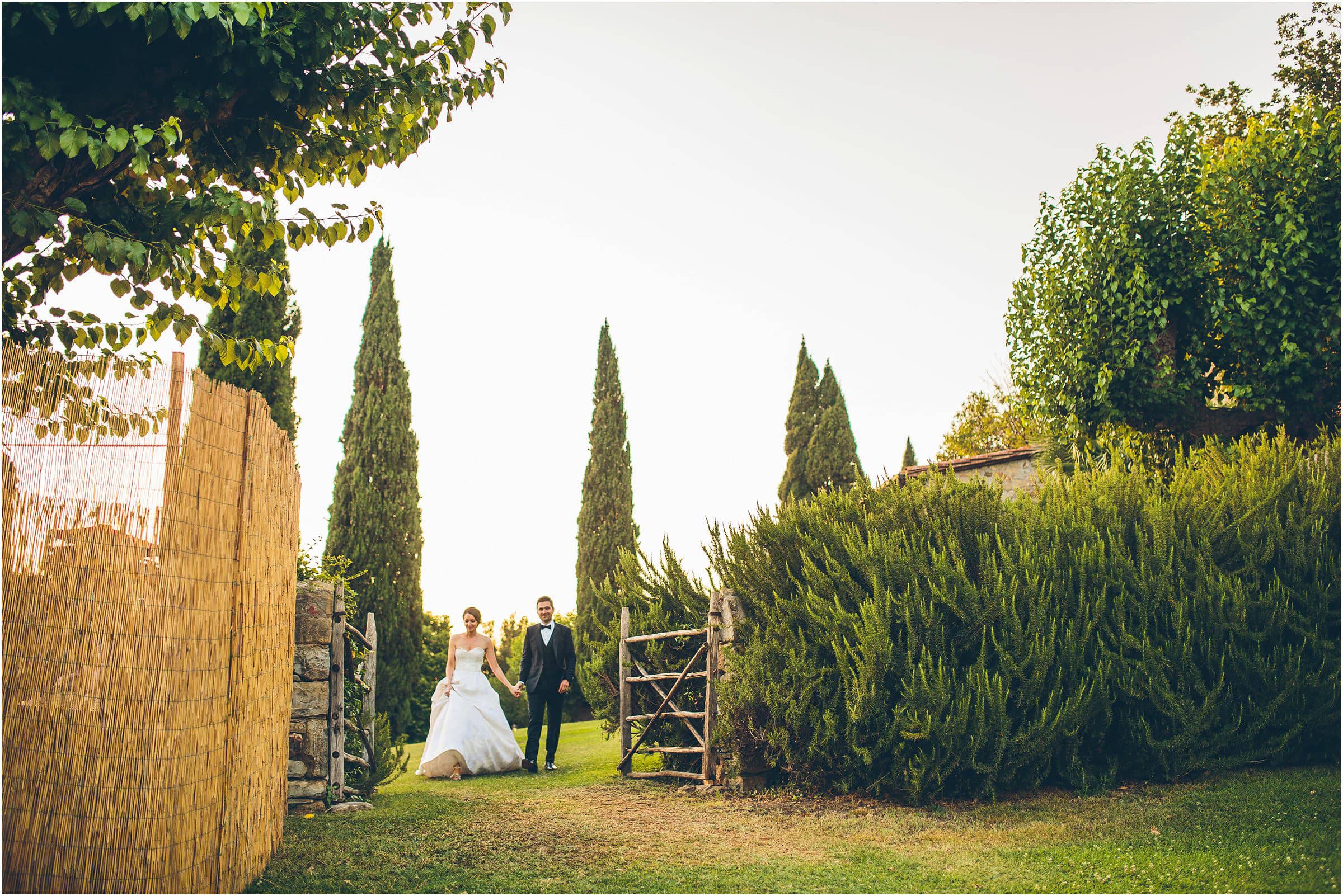 The bride and groom walk through a gate at Castello di Vicarello in Tuscany