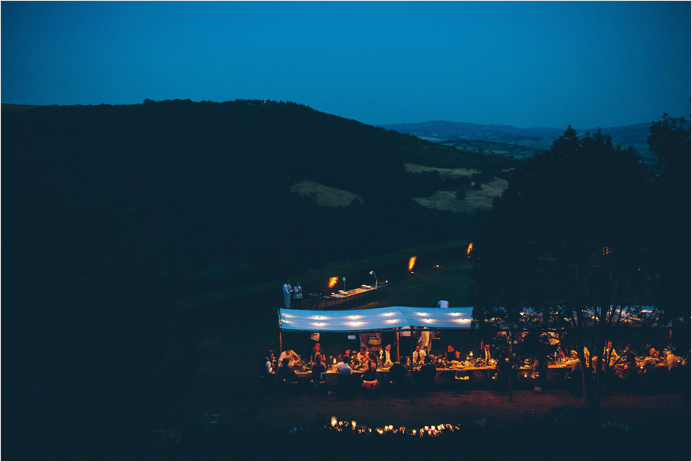 Tables lit outdoors at Castello di Vicarello in Tuscany as night falls