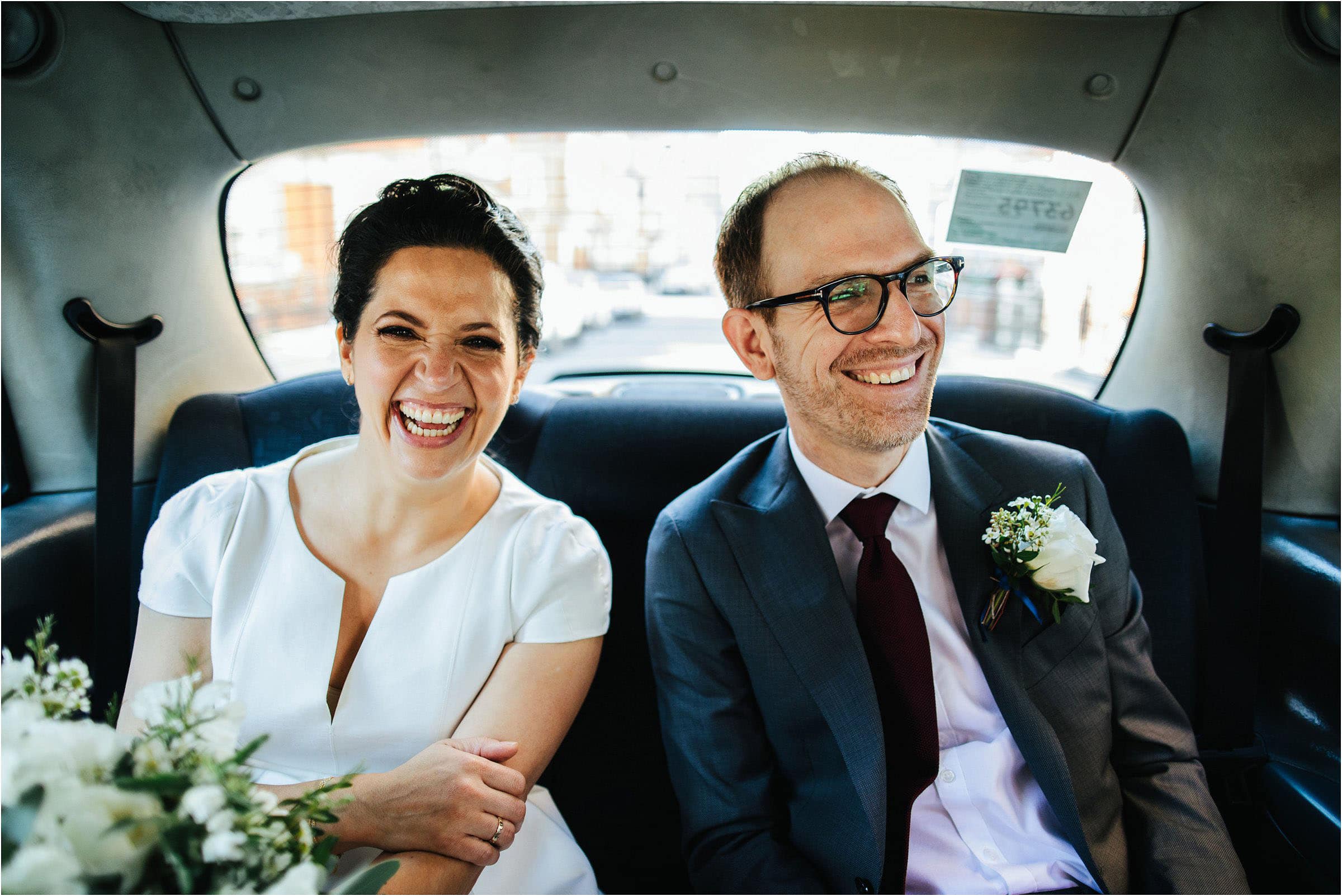 bride and groom in london taxi on their way to their registry office micro wedding